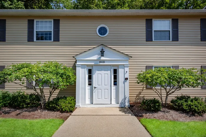 Welcoming entrance of a charming apartment building with classic architecture and manicured greenery.