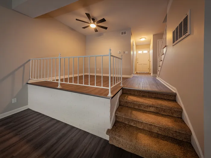 Inviting split-level entryway with elegant hardwood flooring and plush carpeted stairs.