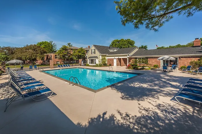 Inviting outdoor pool area surrounded by lush greenery and comfortable lounge chairs at a beautiful apartment community.