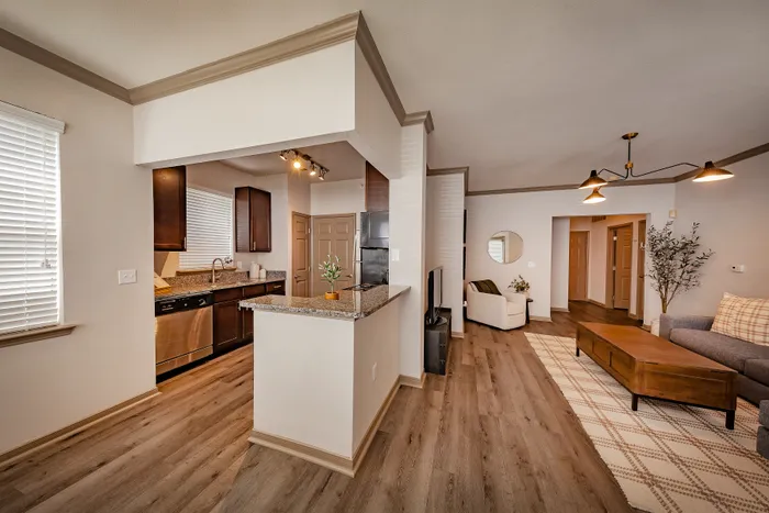 Inviting open-concept apartment showcasing a sleek modern kitchen, bright living area with elegant lighting, and stylish wood flooring.