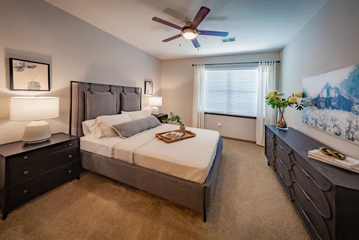 Elegant bedroom with stylish decor, featuring a plush bed, cozy accents, and abundant natural light from a large window.