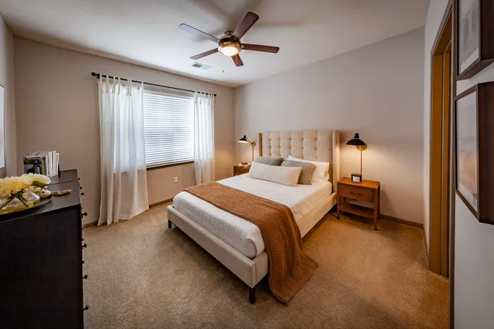 Inviting bedroom with plush bed, elegant headboard, and warm ambient lighting in a cozy apartment.