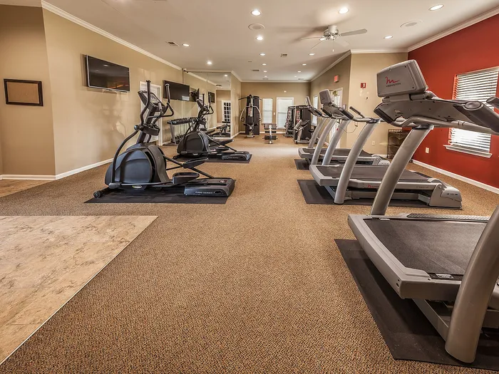Inviting fitness center with modern cardio equipment, large mirrors, and soft lighting creating an energetic workout atmosphere.