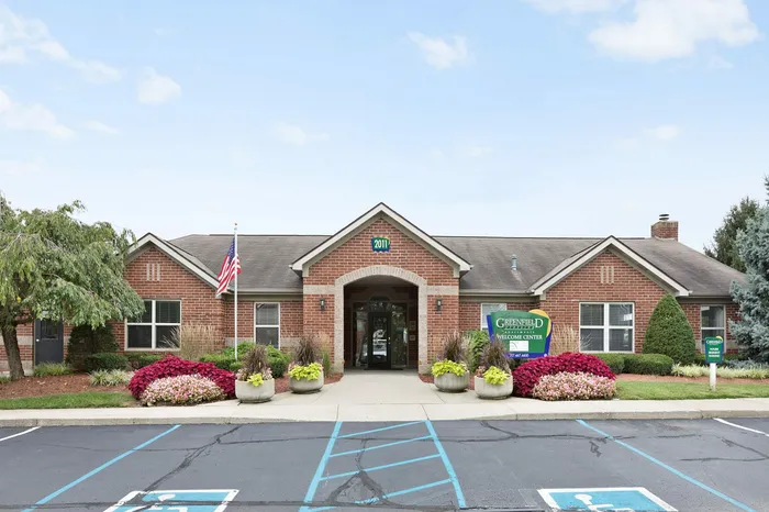 Inviting brick apartment welcome center with charming landscape and vibrant flowers, showcasing community warmth.