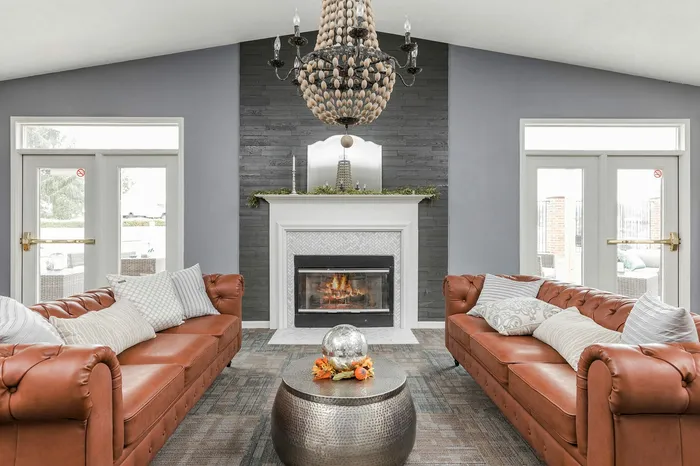 Elegant living room featuring luxurious leather sofas, a grand chandelier, and a cozy fireplace, perfect for stylish relaxation.
