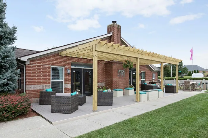Charming outdoor patio with stylish pergola, cozy seating, and inviting brick facade, perfect for relaxing and entertaining.