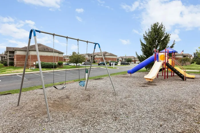 Charming apartment complex featuring a vibrant playground with swings and slides, ideal for families.