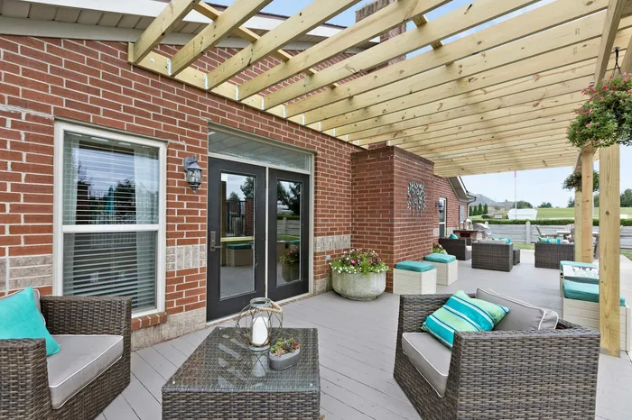 Charming outdoor patio with stylish wicker furniture, vibrant cushions, and inviting natural light under a wooden pergola.