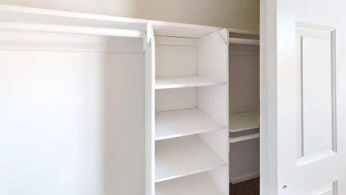Spacious walk-in closet with elegant white shelving and ample storage space.