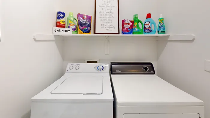 Efficient laundry room with modern washer and dryer, complemented by a neatly organized shelf of cleaning supplies for a tidy home.