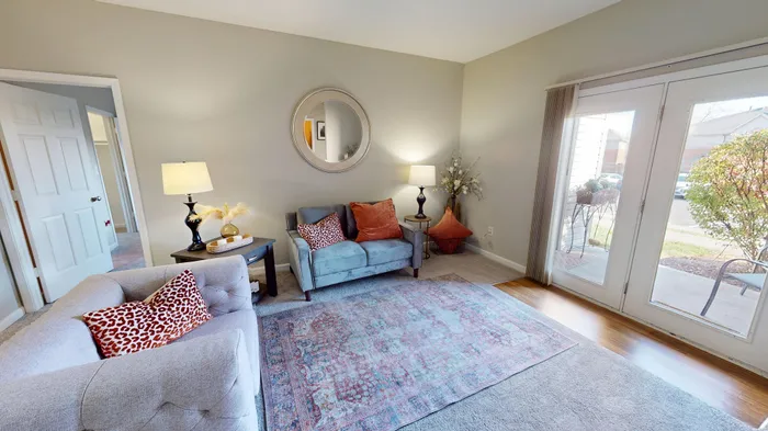 Bright and cozy living room with stylish decor, featuring a plush sofa, chic accent pillows, and large windows opening to a charming view, perfect for relaxation.