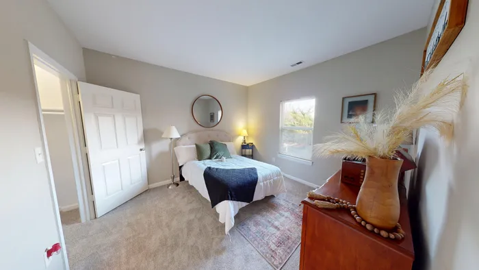 Bright, minimalist bedroom featuring a cozy bed with plush pillows, elegant decor, and warm natural light pouring in.