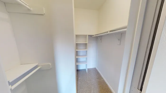 Spacious walk-in closet with built-in shelving and ample hanging space, ideal for organized living.