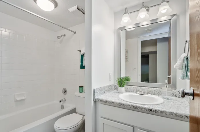 Bright and modern bathroom with sleek white tiles, attractive vanity, and soft lighting fixtures.