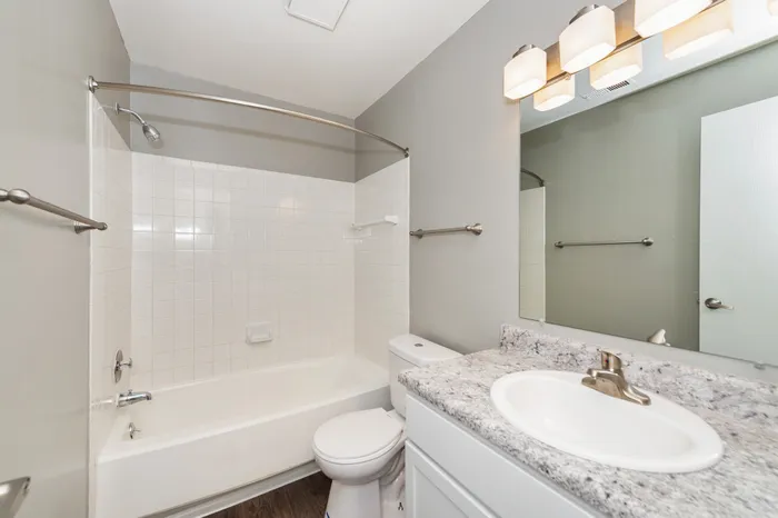 Modern bathroom with elegant lighting, sleek granite countertop, and stylish tiled shower.