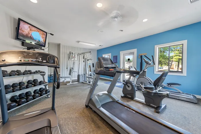 Modern gym equipped with treadmills, exercise bikes, and weight machines in a bright and inviting fitness room.