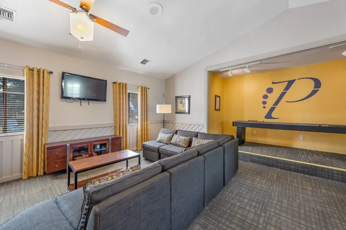 Bright and inviting clubhouse area with modern decor, featuring a large sectional sofa, flat-screen TV. Perfect for relaxation and entertainment.