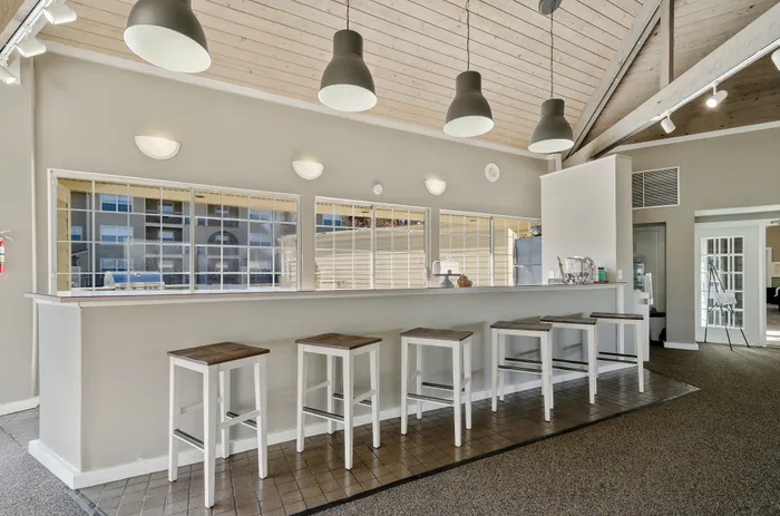 Chic community area with a modern bar setup, featuring stylish bar stools and contemporary lighting fixtures, perfect for social gatherings.