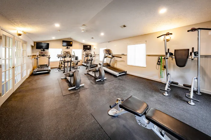 Modern fitness center with state-of-the-art equipment, including treadmills, ellipticals, and strength training machines, in a spacious, well-lit room.