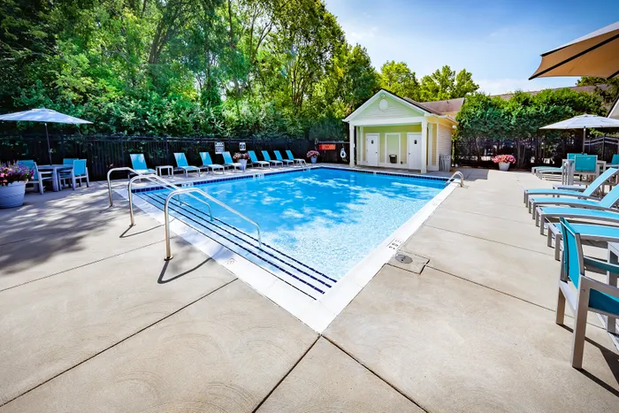 Inviting outdoor pool area surrounded by lush greenery, featuring comfortable lounge chairs and a charming poolside cabana.