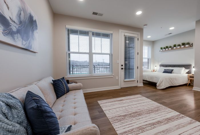 Inviting modern apartment with cozy living room, plush sofa, chic bedroom, and elegant wood flooring, perfect for urban living.