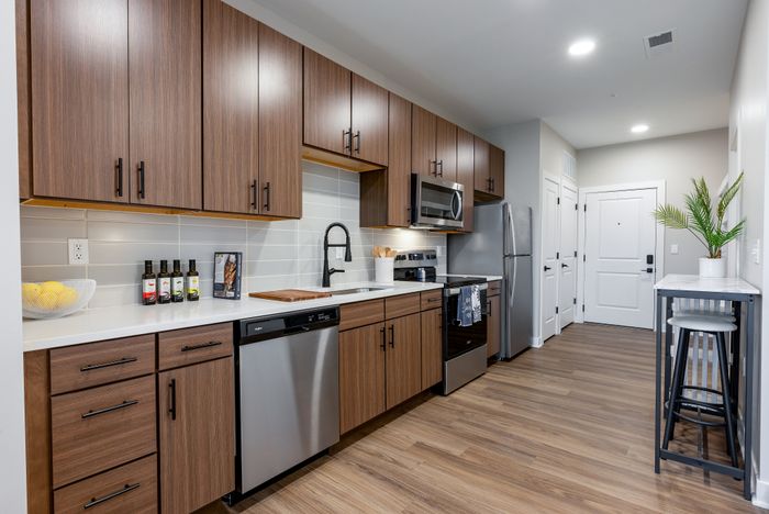 Modern kitchen featuring sleek wooden cabinetry, stainless steel appliances, and a stylish breakfast bar with vibrant decor.