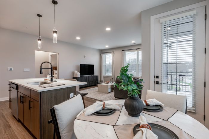 Modern open-concept apartment with elegant kitchen island, cozy living area, and chic dining space, filled with natural light.