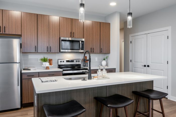 Sleek and modern kitchen with stainless steel appliances, stylish wooden cabinetry, and a chic island.