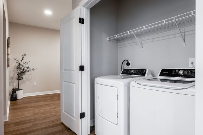 Modern laundry nook with sleek washer and dryer and stylish wood flooring.