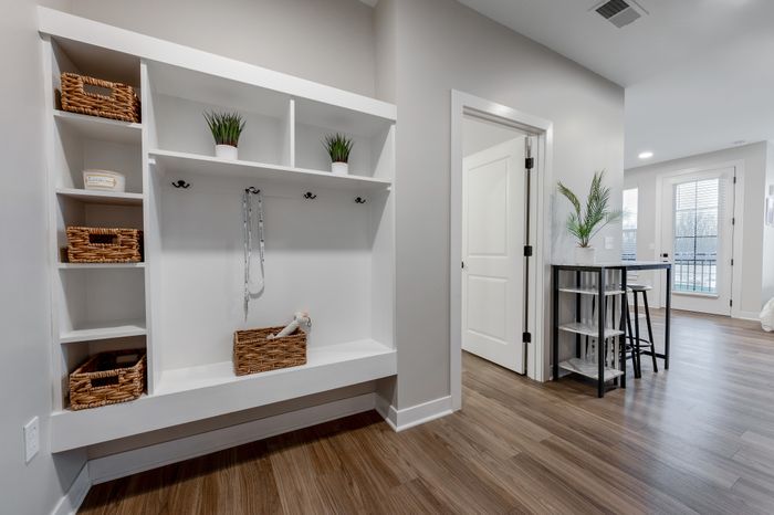 Modern and inviting apartment entrance with elegant shelving and bright natural light, creating a warm and stylish entryway.