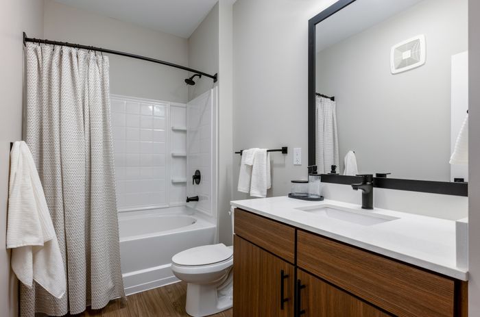 Sleek and modern bathroom featuring a stylish wooden vanity, large mirror, and contemporary fixtures.