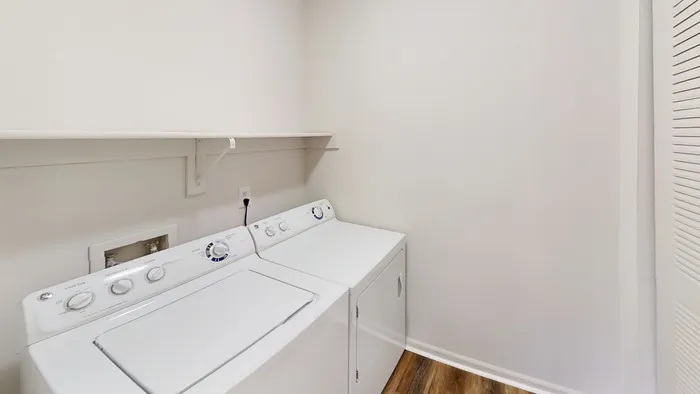 Bright and spacious laundry room featuring modern washer and dryer, complemented by sleek shelving and warm wooden flooring.