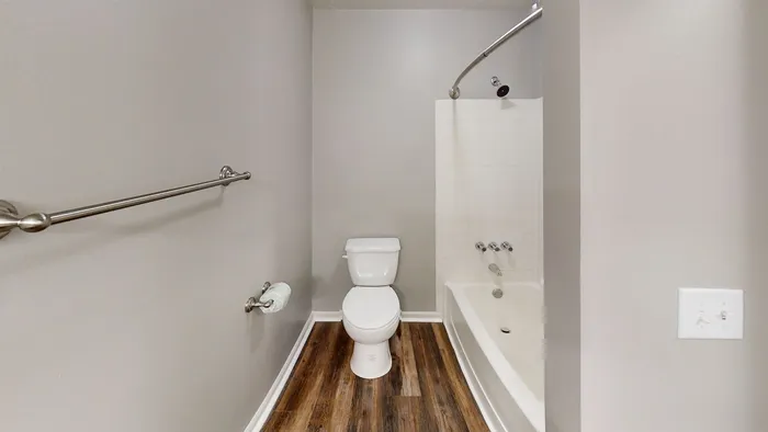 Modern bathroom with sleek fixtures, featuring a pristine bathtub, stylish wood flooring, and calming neutral walls.