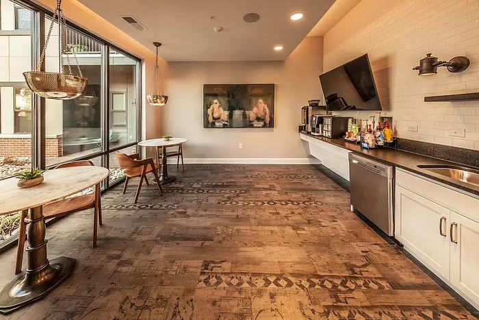Chic and inviting communal space with modern amenities, large windows for natural light, elegant wooden flooring, and a cozy seating area.