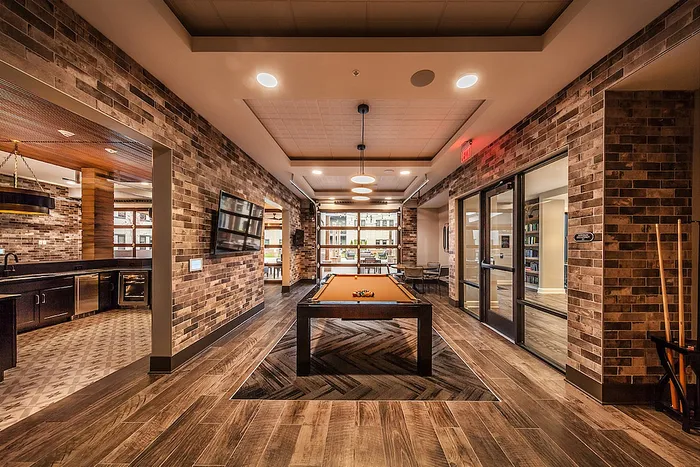 Luxurious entertainment lounge featuring a modern pool table, sleek brick walls, and ambient lighting for a stylish social space.