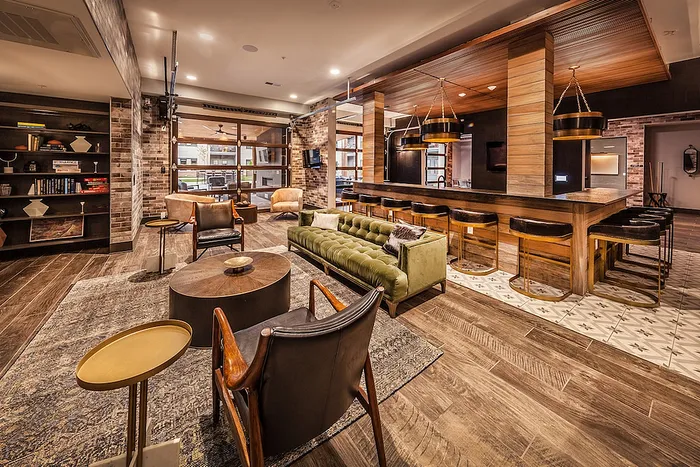 Luxurious open-concept lounge with chic decor, plush seating, and a stylish bar area featuring modern lighting.