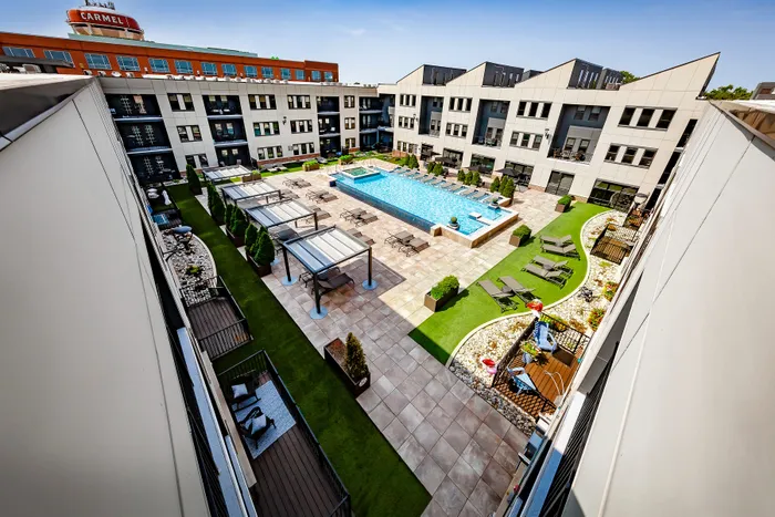 Luxurious apartment courtyard featuring a sparkling swimming pool, elegant lounge areas, and lush landscaping, perfect for relaxation and social gatherings.