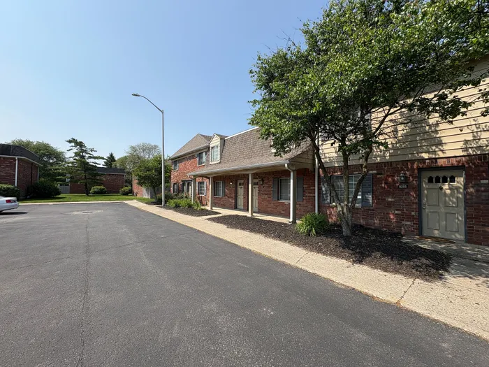 Charming brick apartments with well-maintained landscaping and spacious parking area, offered at Braeburn Village Apartments