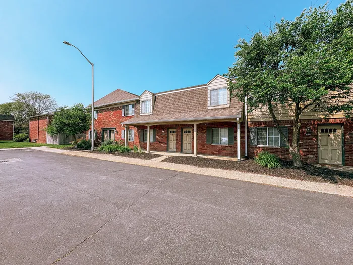 Charming brick townhouse exterior with lush greenery, offering inviting curb appeal at Braeburn Village.