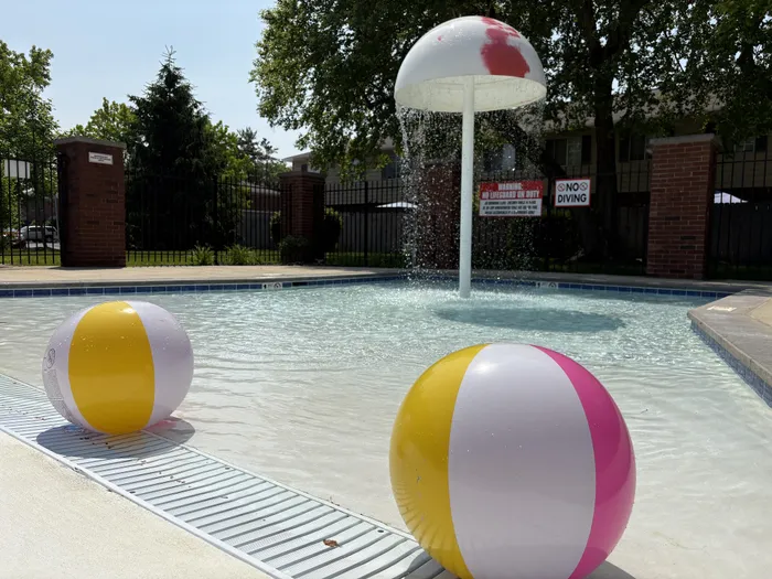 Inviting outdoor pool area featuring a playful mushroom fountain and colorful beach balls at Braeburn Village.