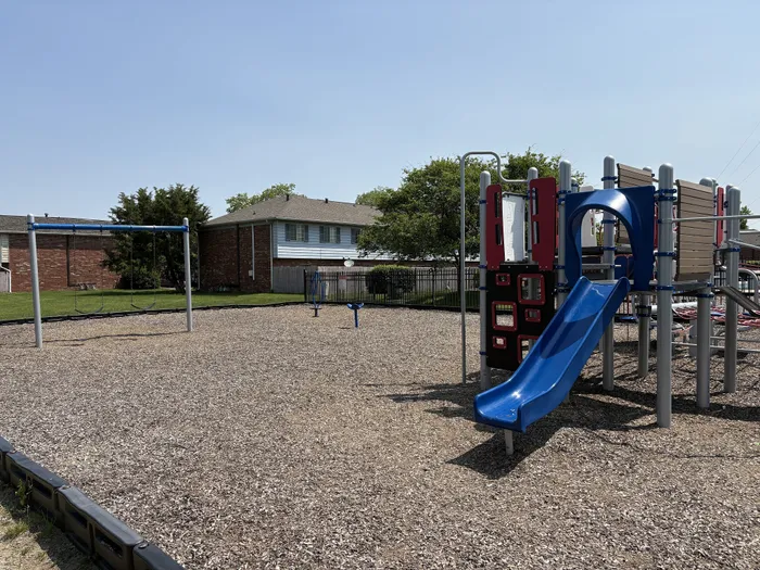 Inviting playground area with vibrant blue slide and swings, nestled in Braeburn Village Apartments