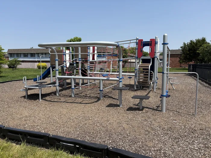 Vibrant outdoor playground featuring climbing structures and slides, set in a sunny Braeburn Village