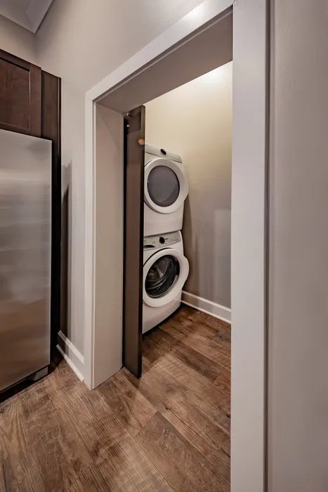 Efficient laundry nook with modern stackable washer and dryer, complementing stylish wood flooring.