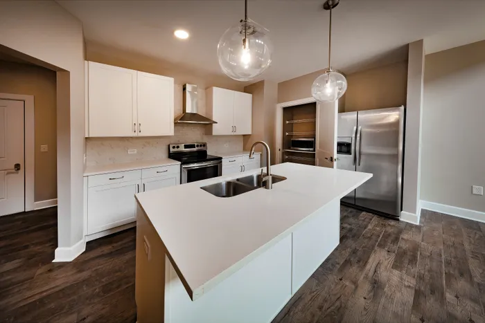 Spacious modern kitchen with sleek white cabinetry, stainless steel appliances, and elegant pendant lighting over a large island.