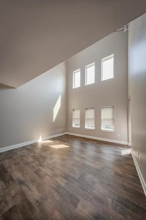 Bright and spacious living area with high ceilings and elegant hardwood floors, highlighted by natural light from multiple windows.