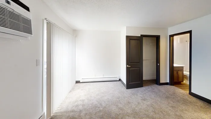 Bright and airy bedroom with plush carpet, large window blinds, a built-in closet, and en-suite bathroom.