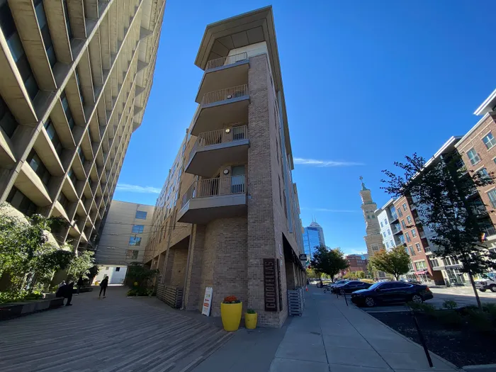 Chic urban apartment building exterior with modern design, located in a vibrant city center under a clear blue sky.