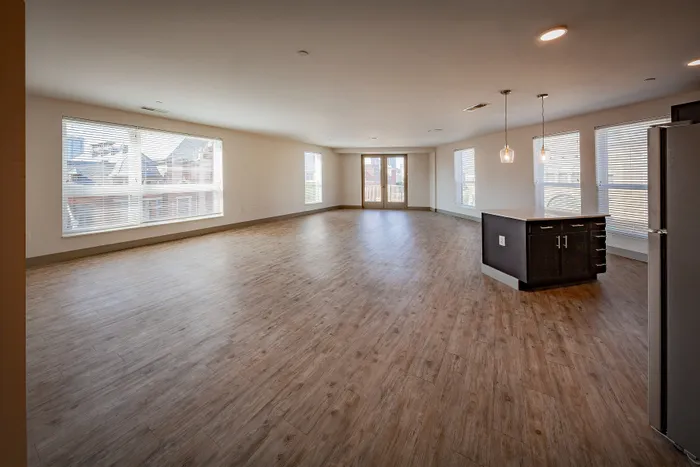 Spacious open-concept living area with elegant wood floors and abundant natural light, ideal for modern living and entertaining.