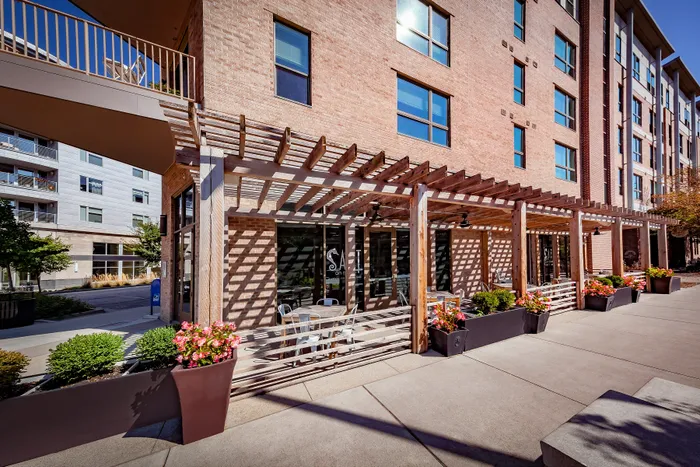 Charming apartment exterior with brick facade and inviting outdoor seating area under a stylish pergola at Salt on Mass.