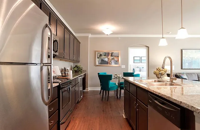 Modern kitchen with stainless steel appliances, elegant granite countertops, and a cozy dining area. Warm wood flooring complements the stylish open-concept layout.